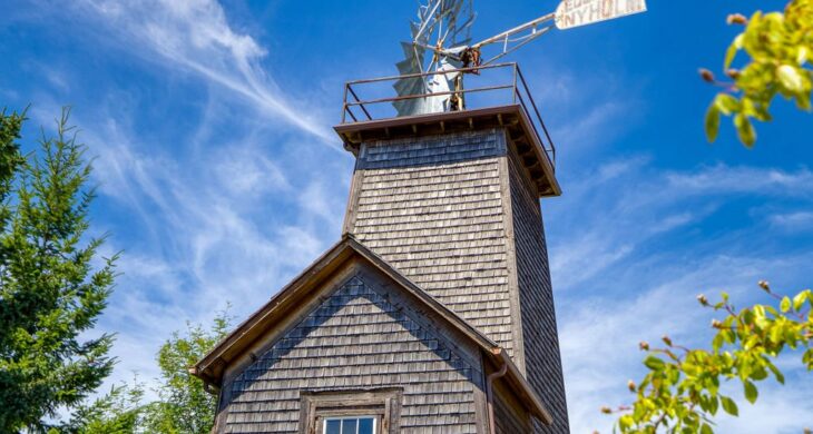 an old wooden windmill in edgewood washington with blue skies and trees behind