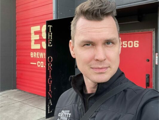 A photo of Chris Staudinger with short hair wearing a black jacked that says, 