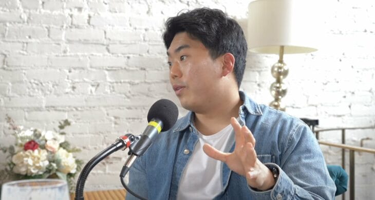 Kevin Lee owner of Third Space Coffee in Tacoma Washington talks into a podcast mic wearing a white tshirt and denim shirt